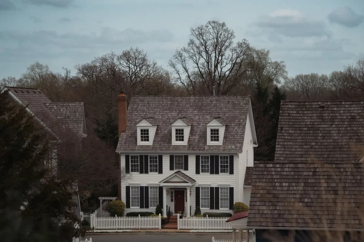 Colonial-style house with a pitched shingle roof in a suburban setting
