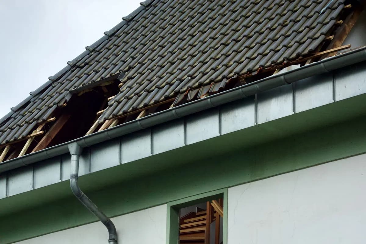 Exterior of a damaged house showing a broken roof and exposed structure