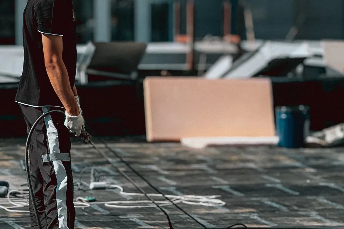 Worker applying a waterproofing coating to a low-slope roof with a roller