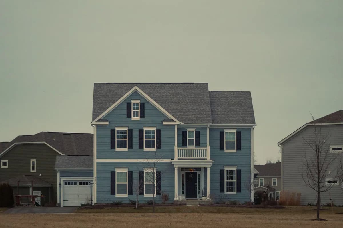 Traditional blue house in a suburban setting under an overcast sky