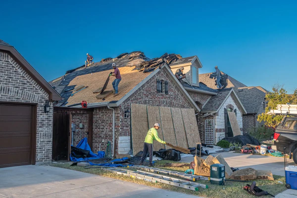 Workers carrying out a roof replacement on a brick house